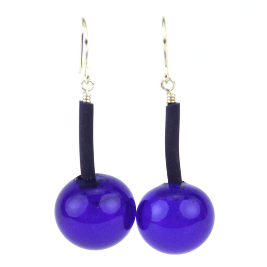 The Aura Earrings in Cobalt, featuring handcrafted deep blue glass beads suspended from flexible tubing with sterling silver hooks, designed for bold elegance and easy wear.