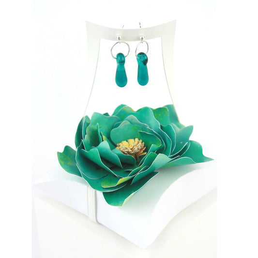 A pair of teal glass and sterling silver earrings displayed in a white gift box, adorned with a handcrafted teal paper flower.