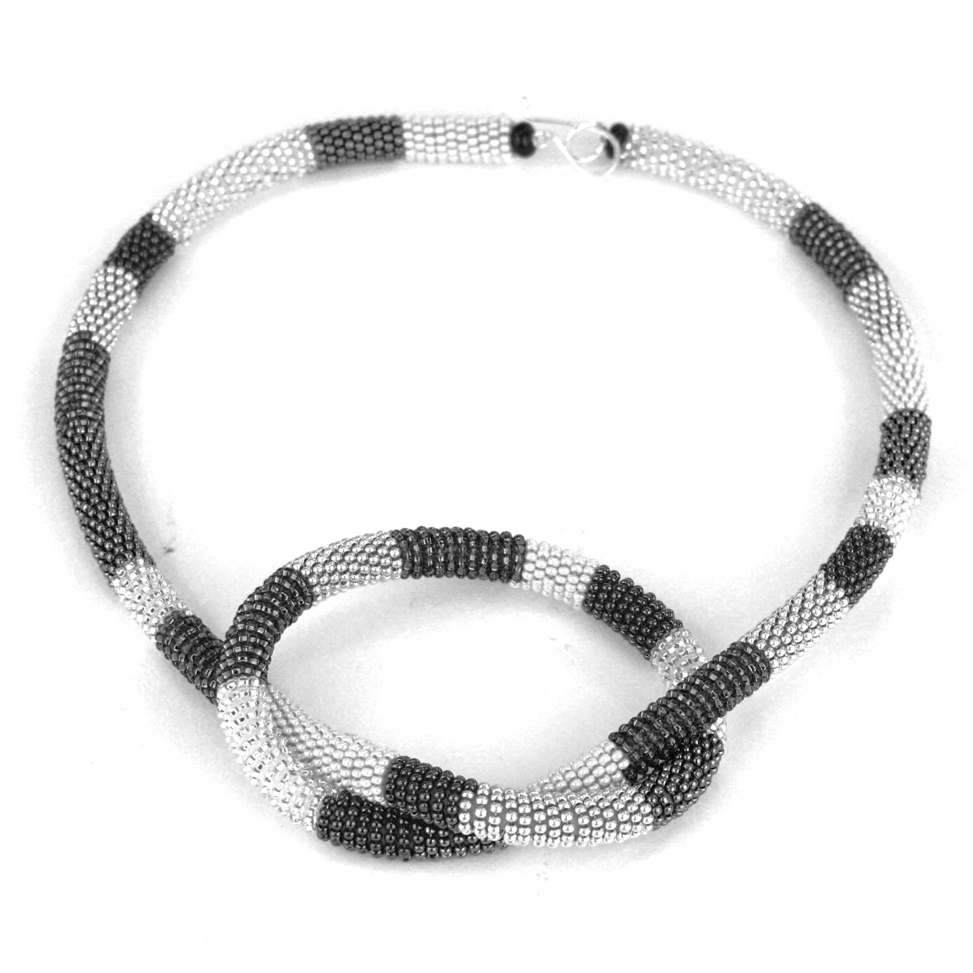 Confetti Knot Necklace in black, white, and silver glass beads on a silicone core, with a sterling silver hook-and-loop closure.