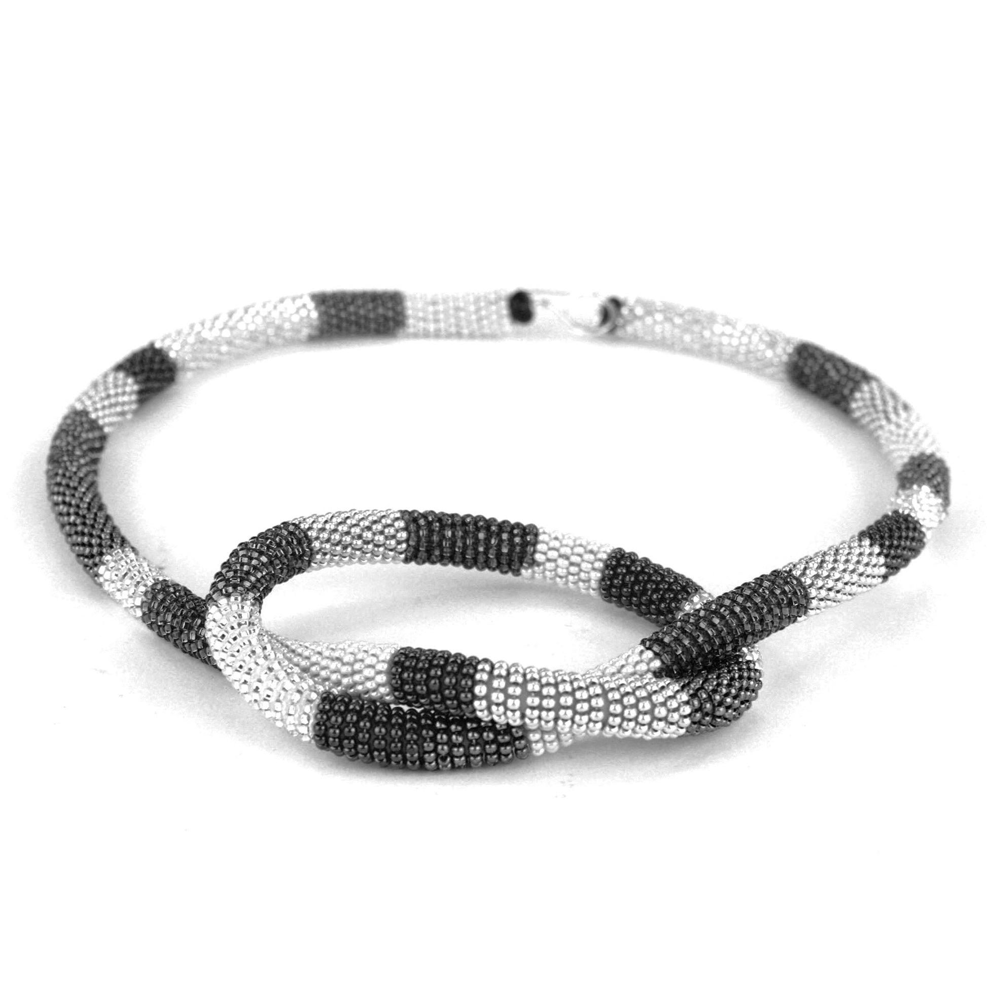 Confetti Knot Necklace in black, white, and silver glass beads on a silicone core, with a sterling silver hook-and-loop closure.