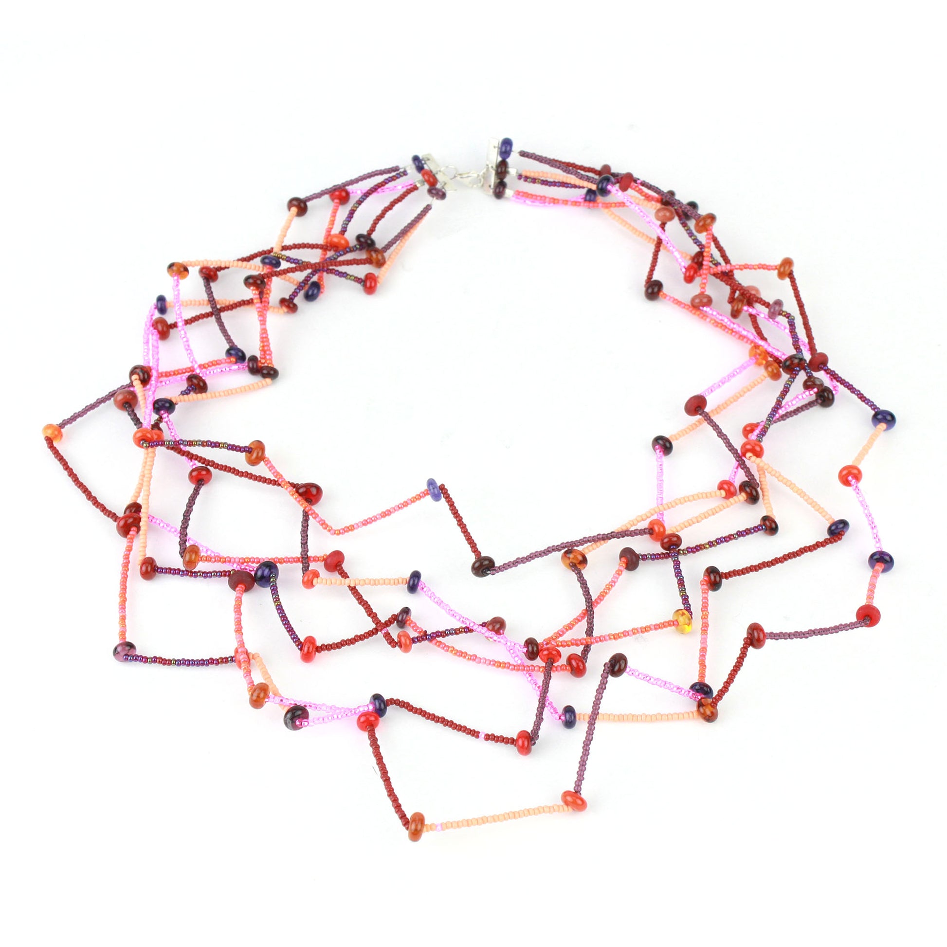 Fiesta Necklace in reds, oranges, pinks and plums. Bold six-strand necklace in red, mauve, and orange hues with handcrafted lampwork beads in a sculptural zig-zag layout.